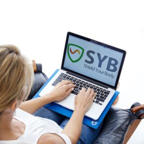 Kigger kvinde over skulderen, hun sidder med SYB Laptop anti-stråling-skjold i blå