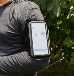 Person bærer SYB løbearmbånd på overarmen med telefon i under træning udendørs