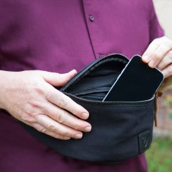 Nærbillede af SYB bæltetaske der åbnes med telefon i hovedrummet