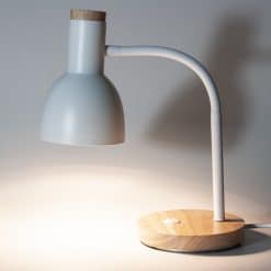 Hvid bordlampe med skærm og buet arm monteret på en rund fod af lyst træ.