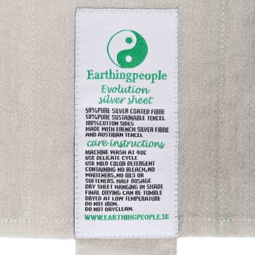 Nærbillede af vaskeinstruks syet på et Earthing Evolution lagen