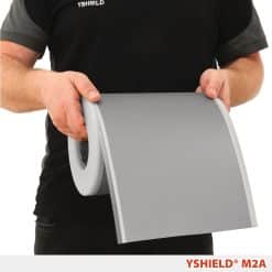 En person holder en rulle grå YSHIELD M2A film, der er rullet let ud.