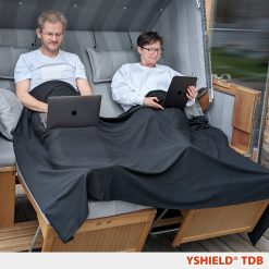 Par der sidder i sofa under et stort blødt EMF-afskærmende tæppe i Black-Jersey fra Yshield (200 x 140 cm)