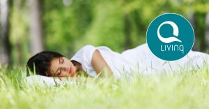 Kvinde sover i græsset og får jordforbindelse og god søvn. Q Living sælger bl.a. Earthing produkter.